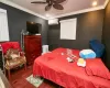 Bedroom with a wall mounted air conditioner, ceiling fan, crown molding, and dark wood-type flooring