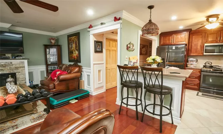 Kitchen with ceiling fan, a stone fireplace, pendant lighting, a breakfast bar area, and appliances with stainless steel finishes