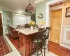 Kitchen featuring hanging light fixtures, ceiling fan, light wood-type flooring, ornamental molding, and a breakfast bar area