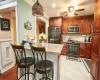 Kitchen with pendant lighting, a breakfast bar, ceiling fan, ornamental molding, and appliances with stainless steel finishes