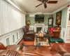 Living room with a stone fireplace, crown molding, hardwood / wood-style flooring, ceiling fan, and a wall unit AC