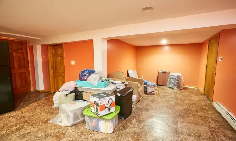 Basement with black fridge and baseboard heating