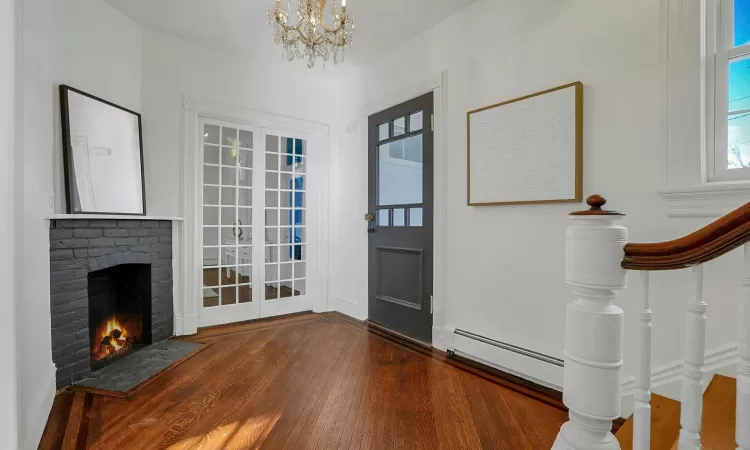 Foyer featuring hardwoor flooring, a brick fireplace, plenty of natural light, and a chandelier