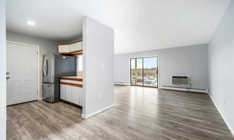 Kitchen featuring a wall unit AC, a baseboard radiator, stainless steel refrigerator, and light hardwood / wood-style flooring