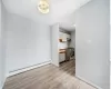 Kitchen with white cabinetry, a baseboard heating unit, light hardwood / wood-style floors, decorative backsplash, and appliances with stainless steel finishes