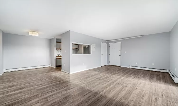 Unfurnished living room with wood-type flooring and baseboard heating