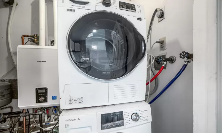 Laundry area featuring tankless water heater and stacked washer and clothes dryer