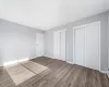 Unfurnished bedroom featuring baseboard heating, hardwood / wood-style floors, and two closets