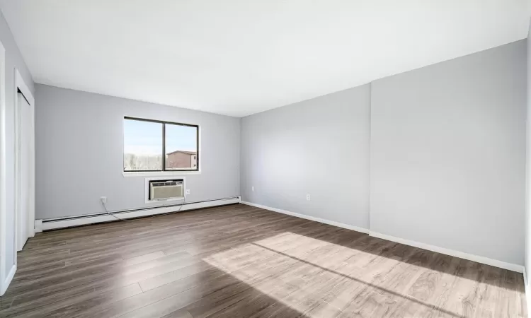 Spare room with hardwood / wood-style floors, a wall mounted air conditioner, and baseboard heating