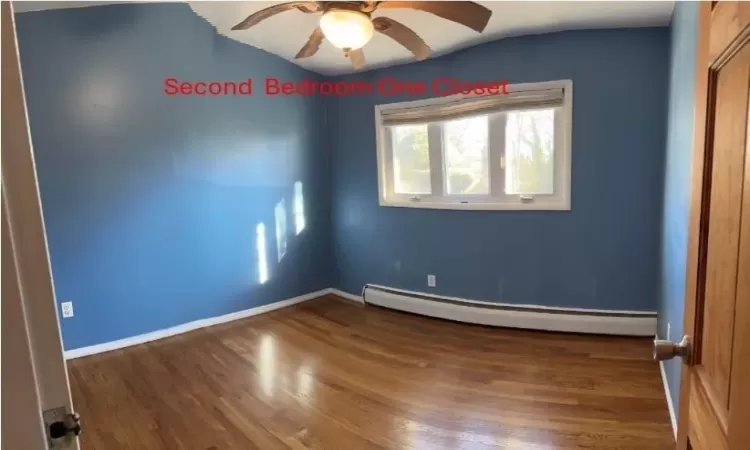 Spare room with ceiling fan, wood-type flooring, and a baseboard radiator