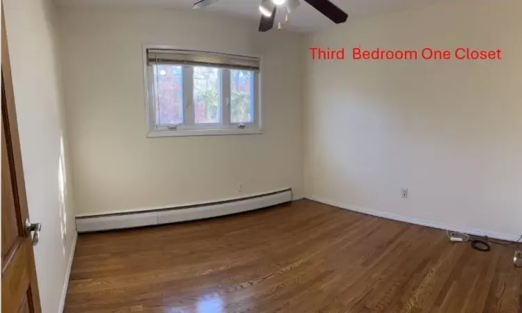 Spare room with ceiling fan, dark wood-type flooring, and a baseboard heating unit