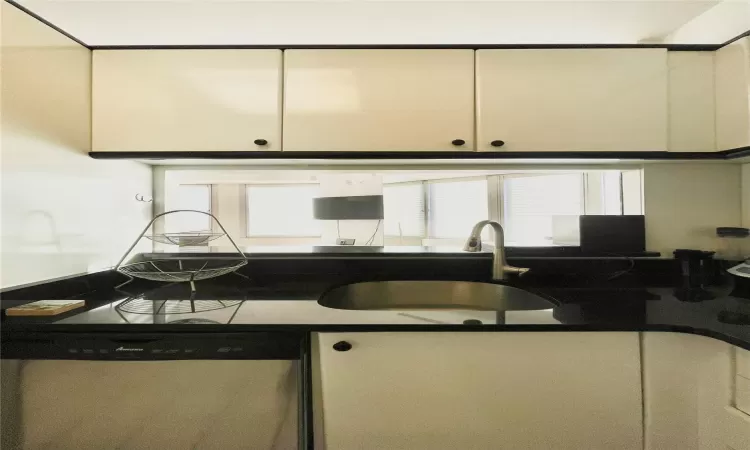 Kitchen with stainless steel dishwasher, white cabinets, and sink