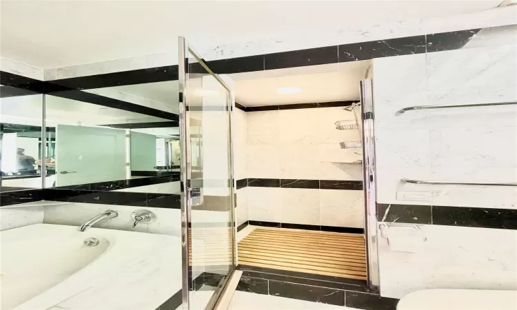 Bathroom featuring tile patterned flooring, shower with separate bathtub, and tile walls