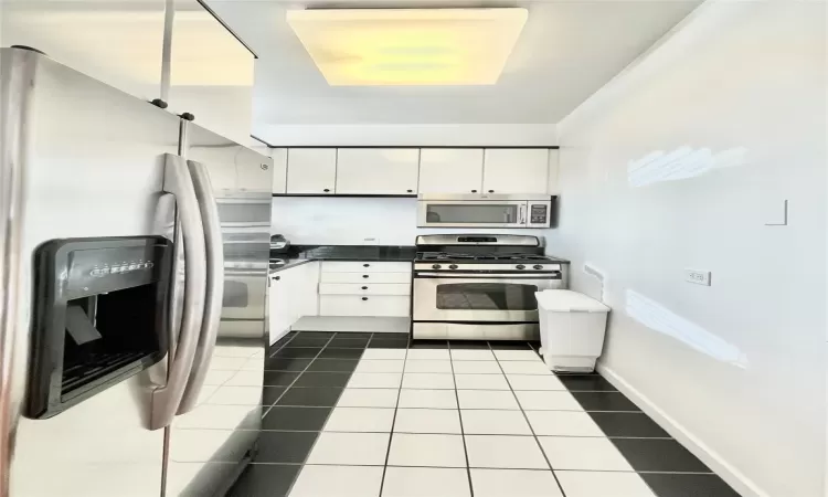 Kitchen featuring tile patterned flooring, white cabinets, and appliances with stainless steel finishes