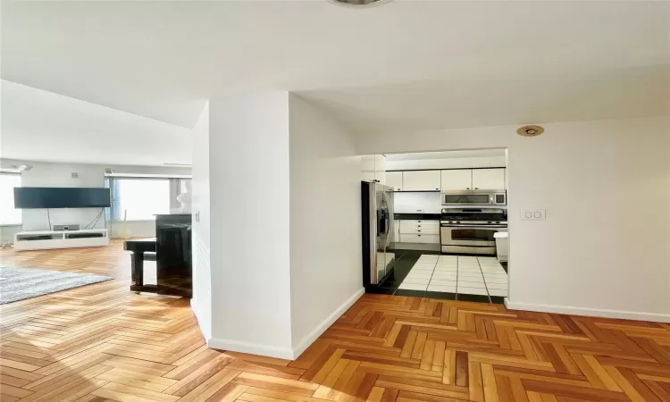 Kitchen featuring white cabinetry, stainless steel appliances, and light parquet floors