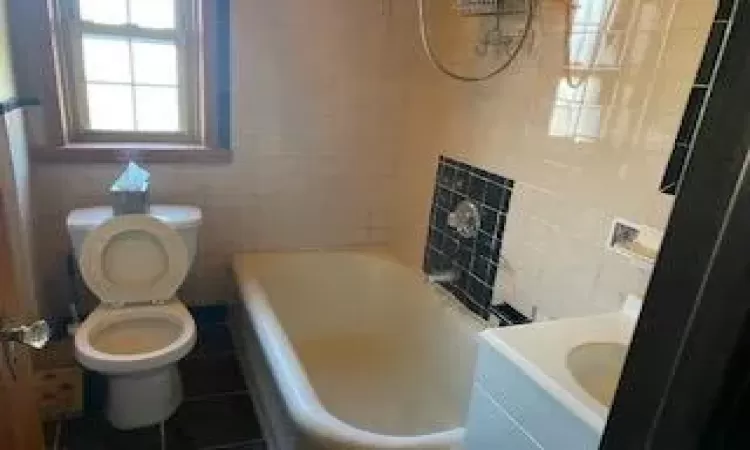 Bathroom featuring tile patterned flooring, vanity, toilet, and tile walls