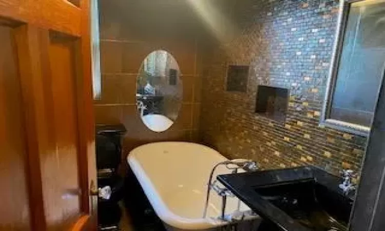 Bathroom with tasteful backsplash, tile walls, and a tub