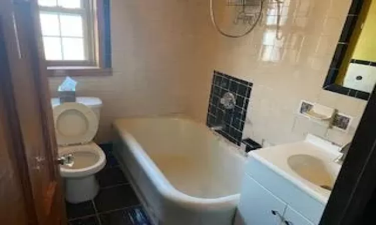 Bathroom with tile patterned floors, vanity, tile walls, and toilet