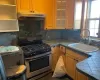 Kitchen featuring stainless steel stove, tile counters, tasteful backsplash, and sink