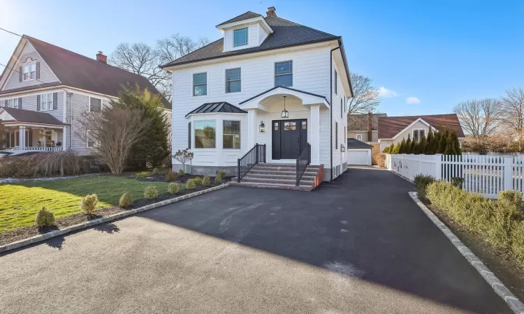 View of front of home with a garage, an outdoor structure, and a front lawn