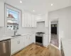 Kitchen featuring white cabinetry, sink, stainless steel appliances, backsplash, and custom exhaust hood