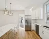 Kitchen with stainless steel appliances, white cabinetry, and hanging light fixtures