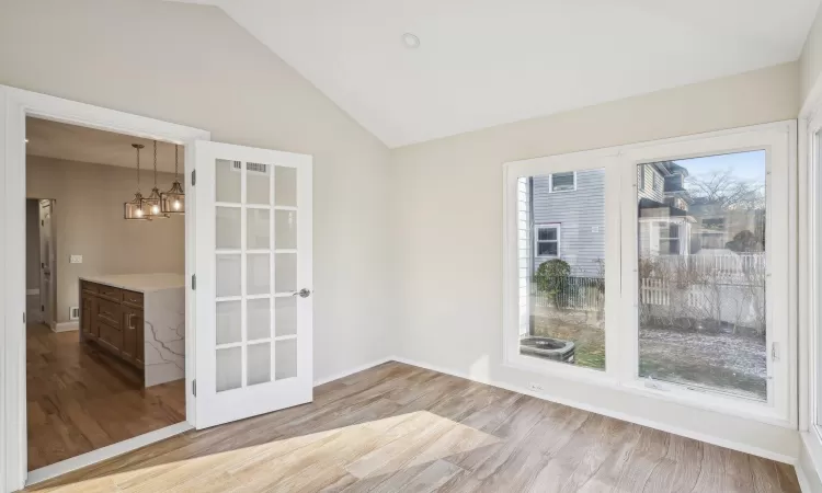 Unfurnished room featuring a notable chandelier, light hardwood / wood-style flooring, and vaulted ceiling