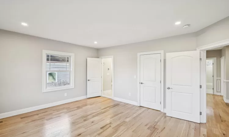 Primary bedroom with light hardwood / wood-style flooring and a healthy amount of sunlight