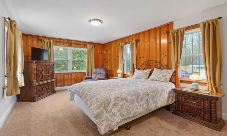 Bedroom featuring light carpet and wooden walls