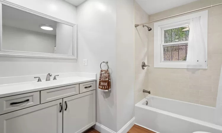 Bathroom featuring hardwood / wood-style flooring, shower / bath combination with curtain, and vanity