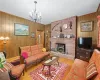 Living room featuring a notable chandelier, wood walls, a wood stove, and light hardwood / wood-style flooring