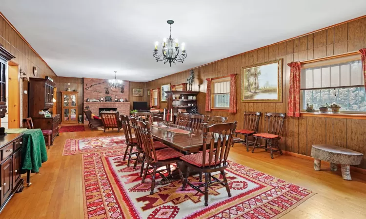 Dining room with a brick fireplace, light hardwood / wood-style flooring, and a chandelier