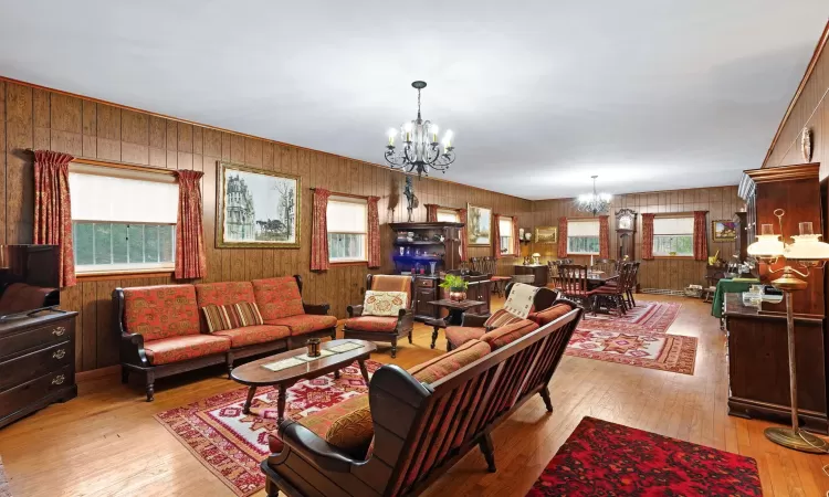 Living room with a notable chandelier, wood walls, and light hardwood / wood-style flooring