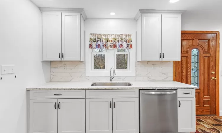 Kitchen featuring dishwasher, white cabinets, and sink