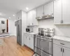 Kitchen with decorative backsplash, light stone countertops, light hardwood / wood-style flooring, and appliances with stainless steel finishes