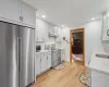 Kitchen featuring sink, light hardwood / wood-style floors, light stone counters, white cabinetry, and stainless steel appliances