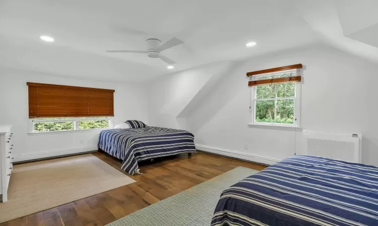 Bedroom featuring baseboard heating, multiple windows, ceiling fan, and wood-type flooring