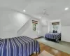 Bedroom with vaulted ceiling, ceiling fan, baseboard heating, wood-type flooring, and a wall unit AC