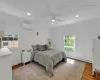 Bedroom featuring light hardwood / wood-style floors, a wall unit AC, ceiling fan, and a baseboard radiator