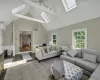 Living room featuring ceiling fan, a healthy amount of sunlight, an AC wall unit, and lofted ceiling with skylight