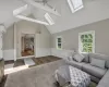 Living room featuring vaulted ceiling with skylight, an AC wall unit, a wealth of natural light, and ceiling fan