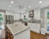 Kitchen with wall chimney exhaust hood, stainless steel appliances, white cabinetry, a kitchen island, and plenty of natural light