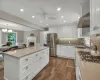 Kitchen with sink, white cabinetry, stainless steel appliances, and range hood