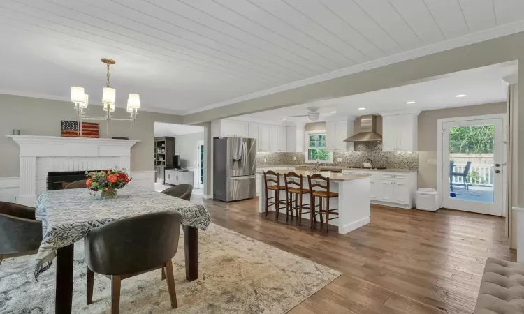 Dining room with hardwood / wood-style flooring, wood ceiling, ornamental molding, and a brick fireplace