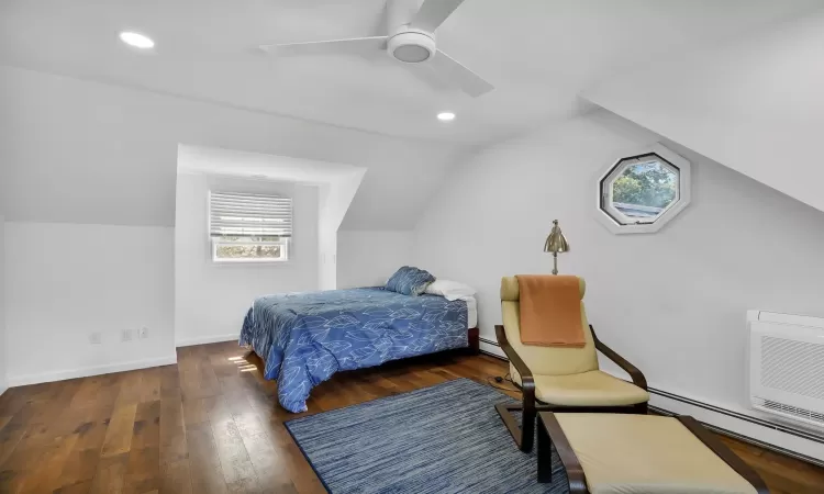 Bedroom with ceiling fan, dark hardwood / wood-style flooring, a baseboard heating unit, an AC wall unit, and vaulted ceiling