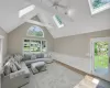 Living room featuring ceiling fan, light hardwood / wood-style flooring, and lofted ceiling with skylight