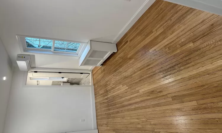 Empty room with light hardwood / wood-style floors, radiator, and a wall mounted AC