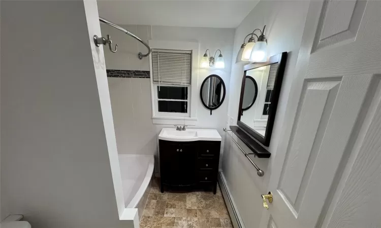 Bathroom with vanity, shower / bath combination, and baseboard heating