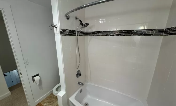 Bathroom with toilet, tile patterned flooring, and tiled shower / bath