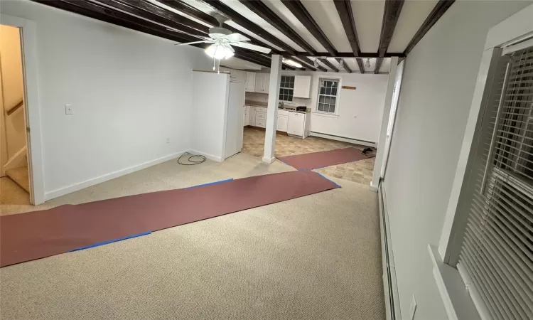 Basement with a baseboard radiator and light colored carpet